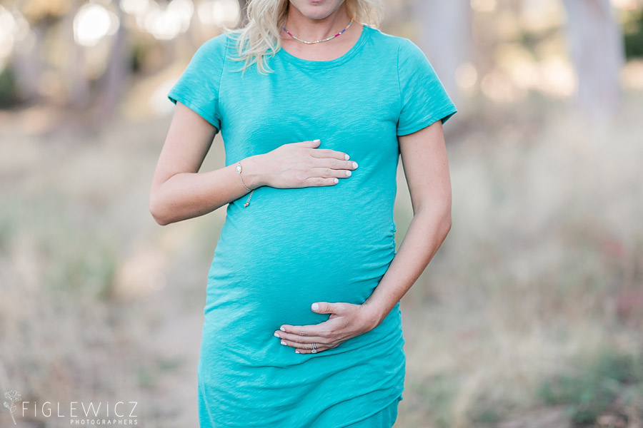 mother holding tummy in bright blue dress