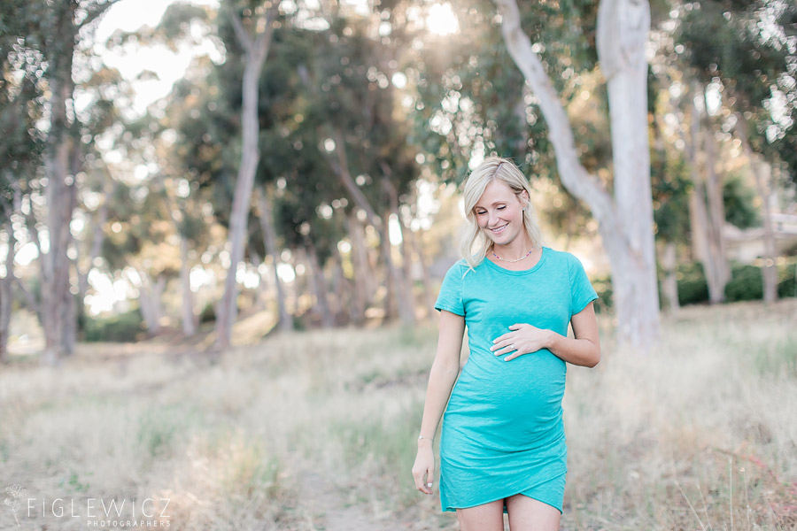 mother standing in palos verdes holding tummy in bright blue dress