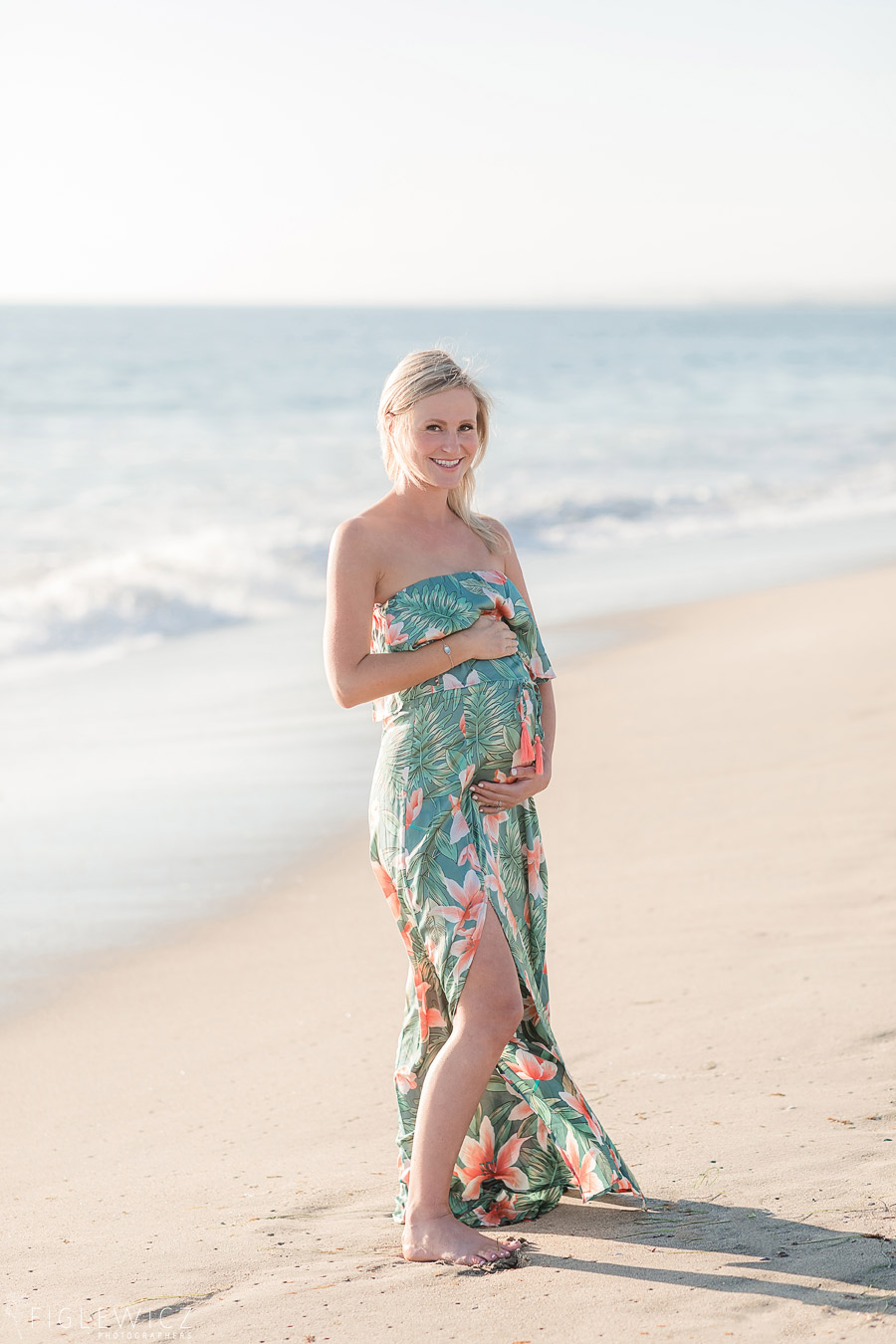 mother walking along beach holding tummy